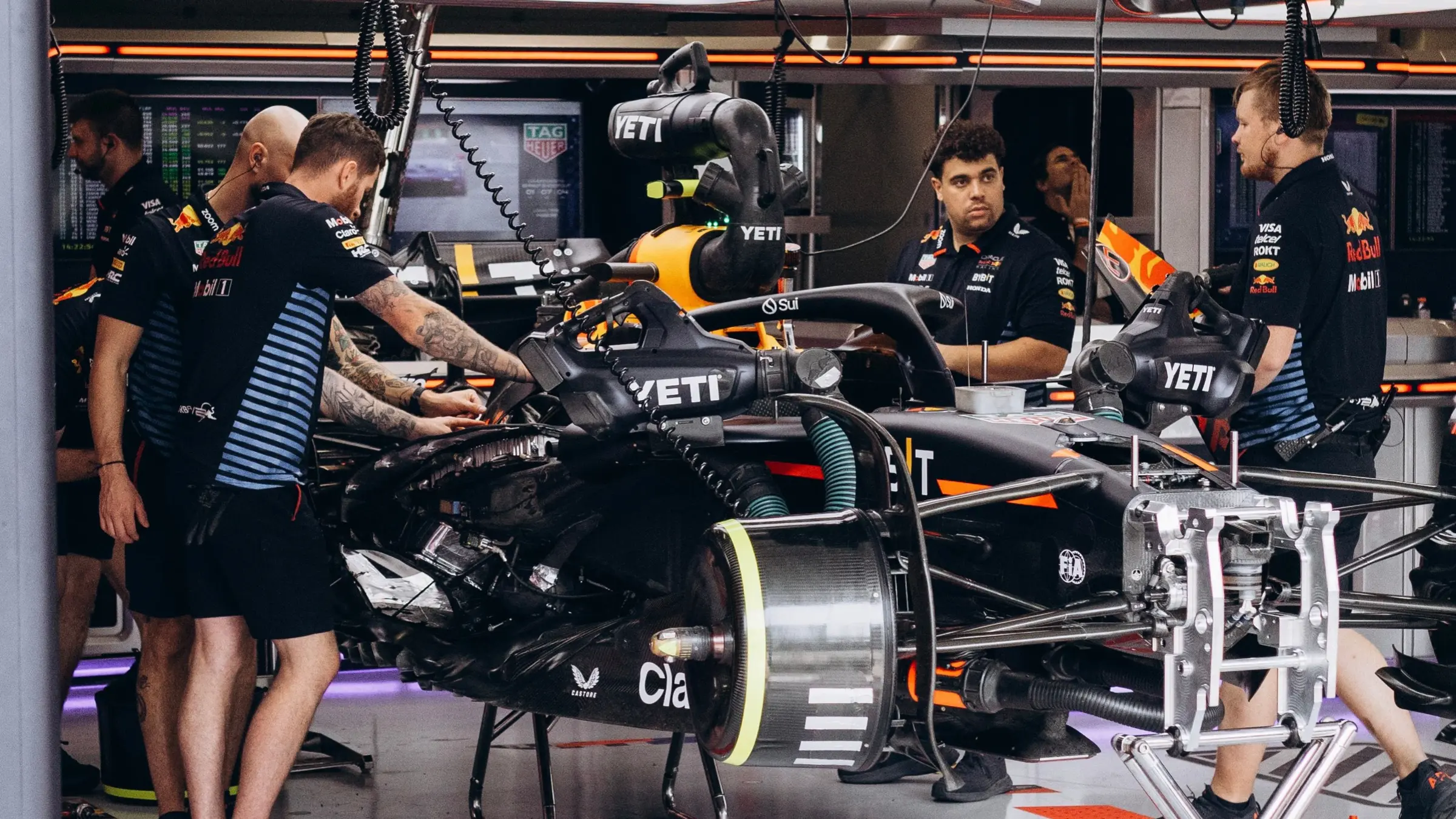 Formula 1 mechanics working on a racing car inside the Oracle Red Bull Racing garage.